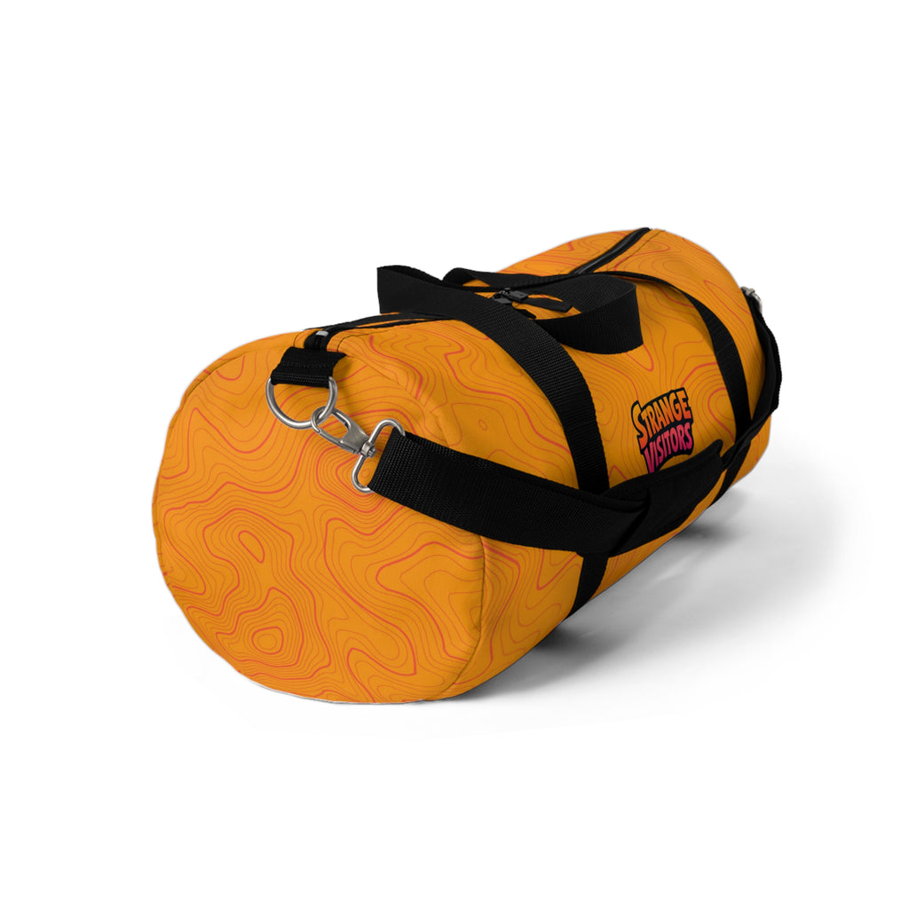 Pack For The Unknown duffel: an orange barrel-style duffel bag covered in topographic contour lines with the Strange Visitors logo, black zipper and black carry handles (view 3)