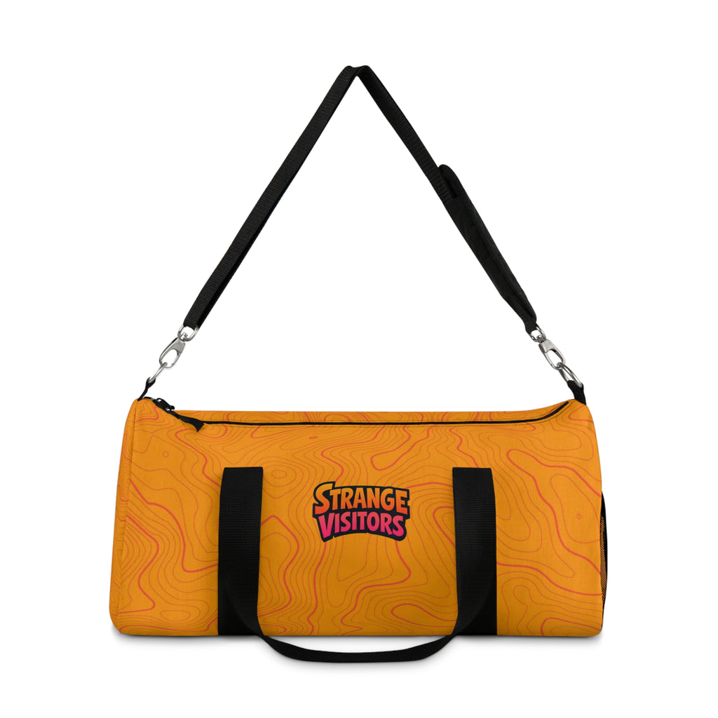 Pack For The Unknown duffel: an orange barrel-style duffel bag covered in topographic contour lines with the Strange Visitors logo, black zipper and black carry handles (view 2)